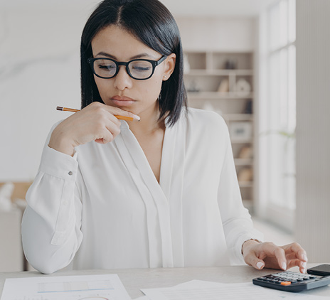 Business woman in glasses counting profit on calculator