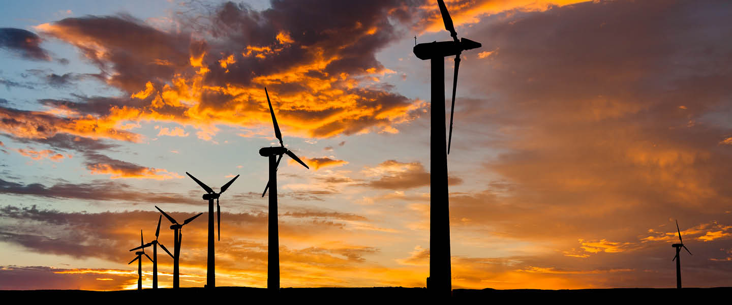 Windmolens bij een zonsondergang mooi in beeld door het oranje tegenlicht. 