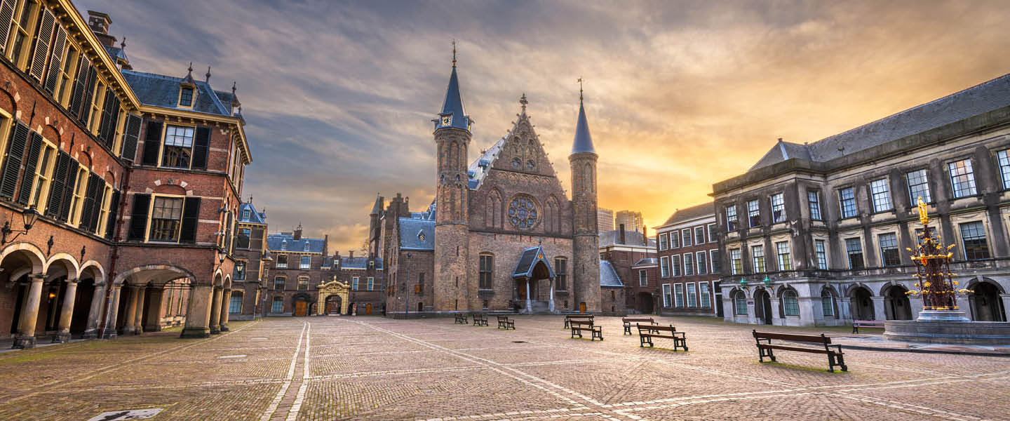 Met mooi oranje tegenlicht door een ondergaande zon. Kijk je vanuit het binnenhof naar de ingang van de ridderzaal toe. 